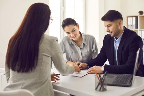 Happy couple meeting realtor and signing lease, mortgage or house purchase agreement